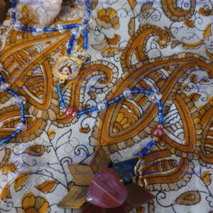 A close up of a handbeaded rosary on an ornate cloth background.